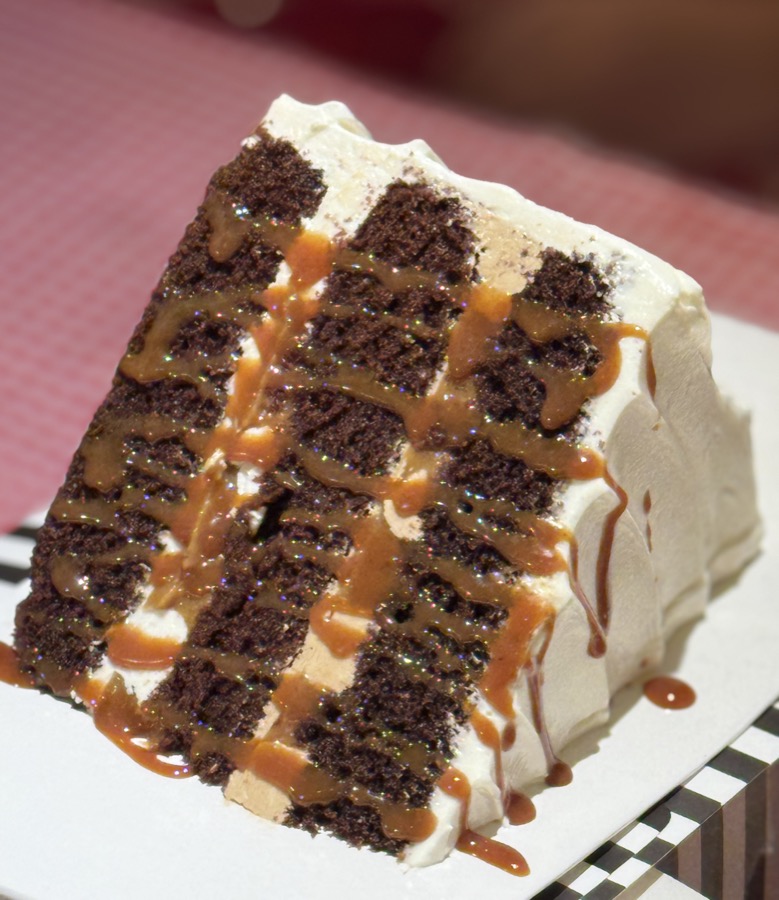 A slice of chocolate layer cake with buttercream and salted caramel drizzle
