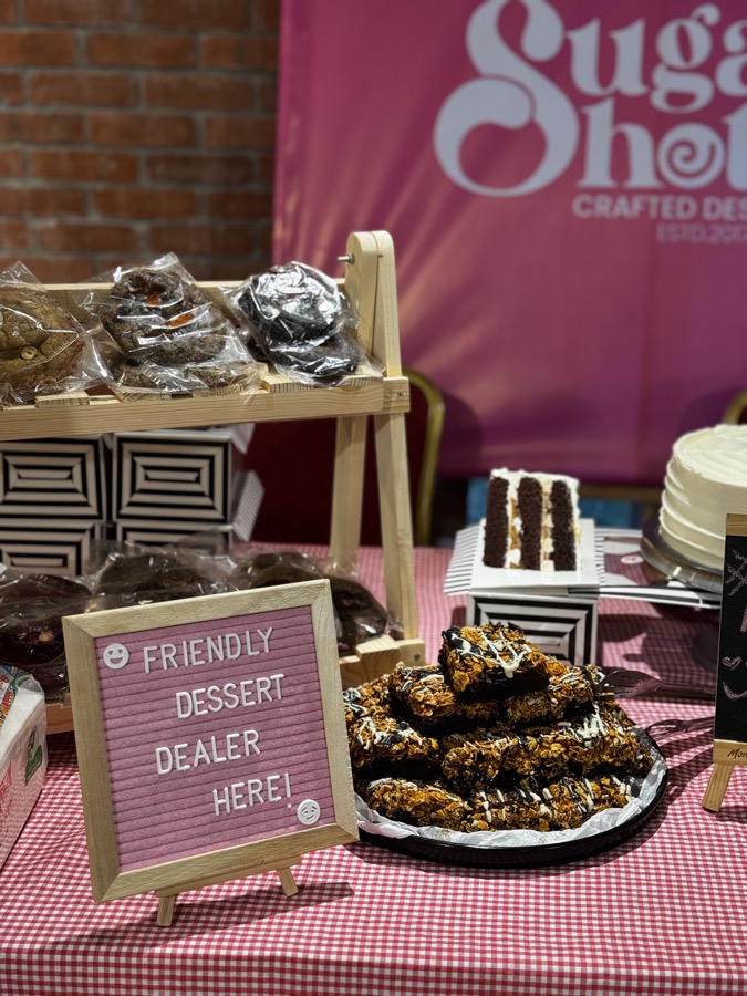 Cookies, brownies and cakes on a Sugar Shots pop-up table with a Friendly Dessert Dealer Here sign